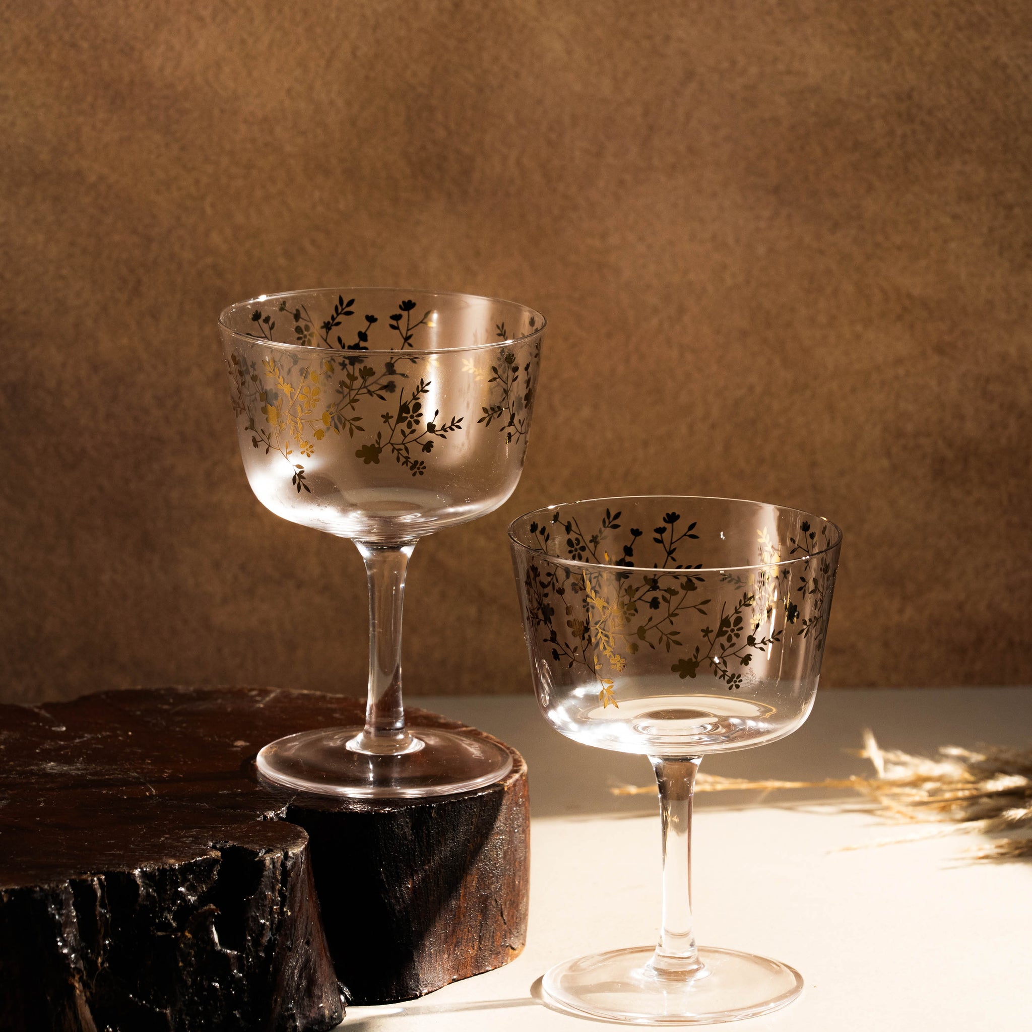 Two decorative glasses on a wooden surface with a brown background