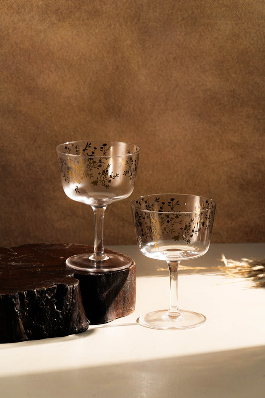 Two decorative glasses on a wooden surface with a brown background