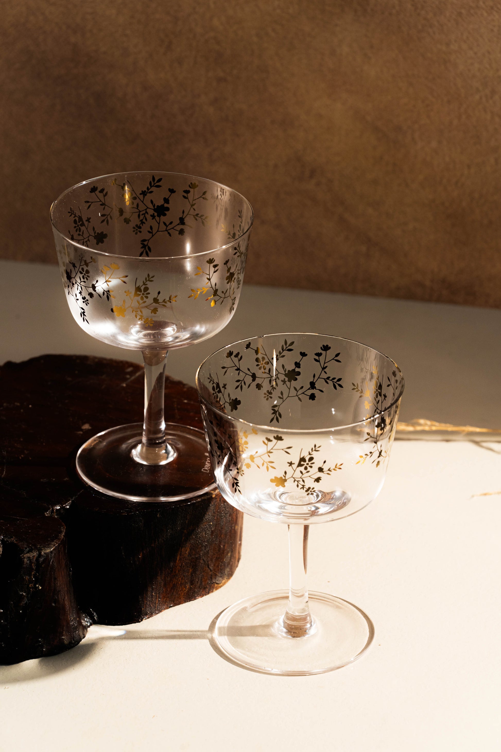 Two elegant glass goblets with floral patterns on a wooden surface.