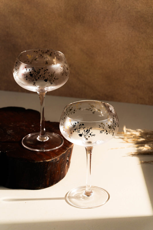Two elegant cocktail glasses with decorative patterns on a textured surface.