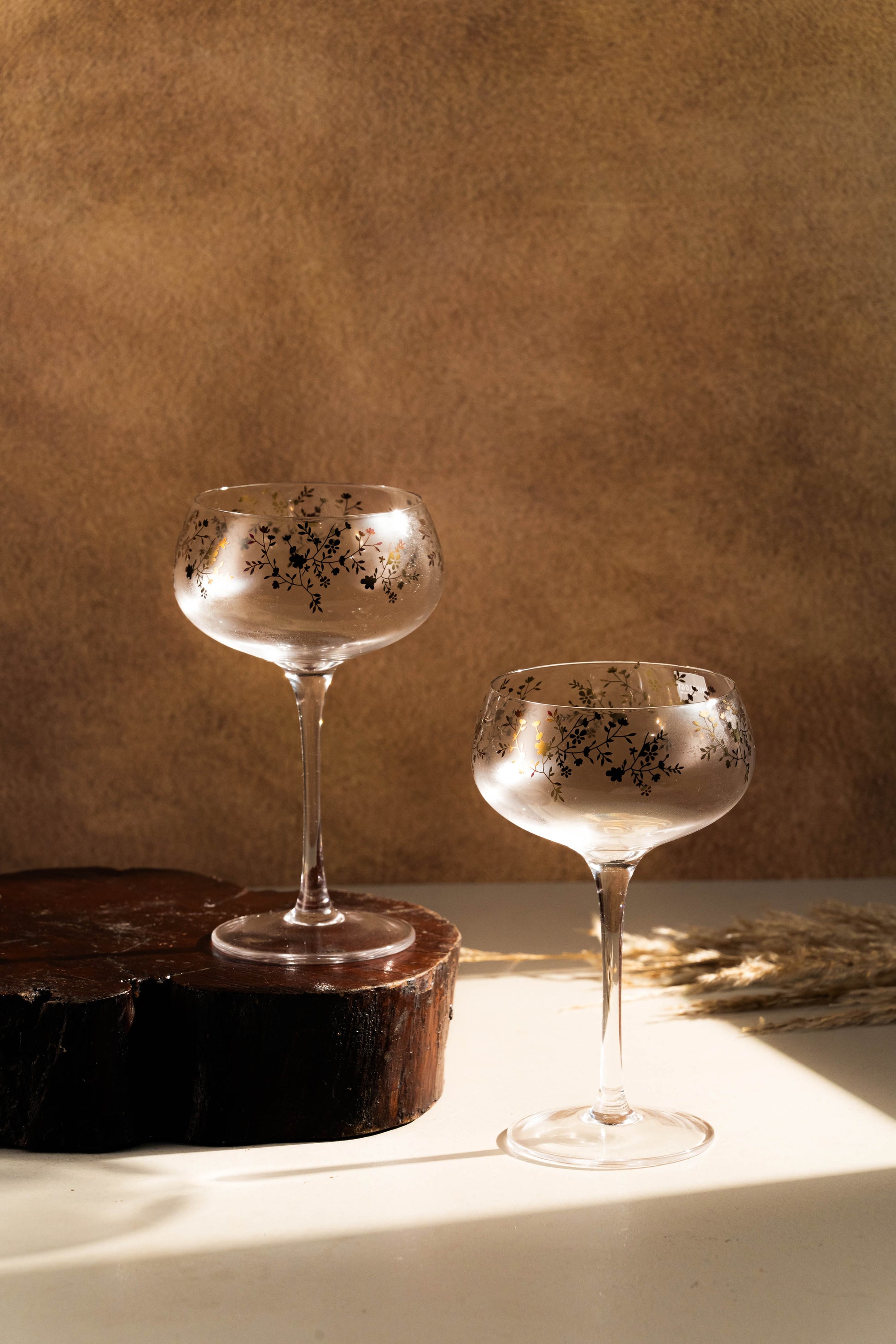 Two decorative glasses with speckled design on a textured surface with a brown background