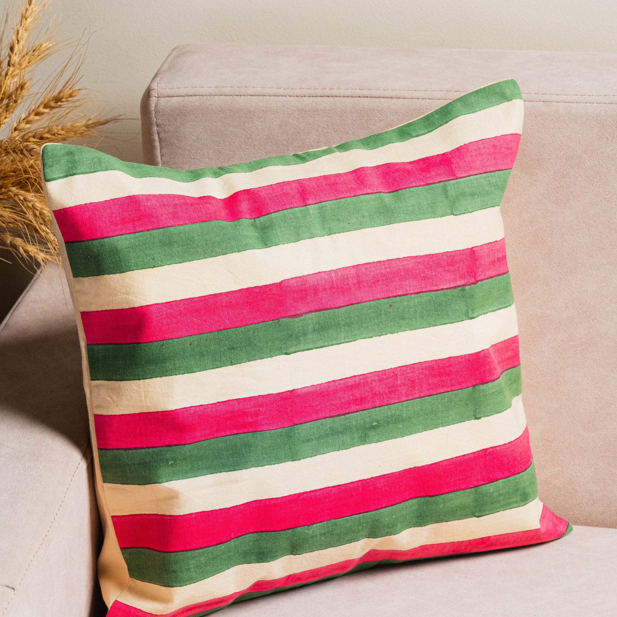 Striped pillow with red, green, and beige colors on a beige couch.