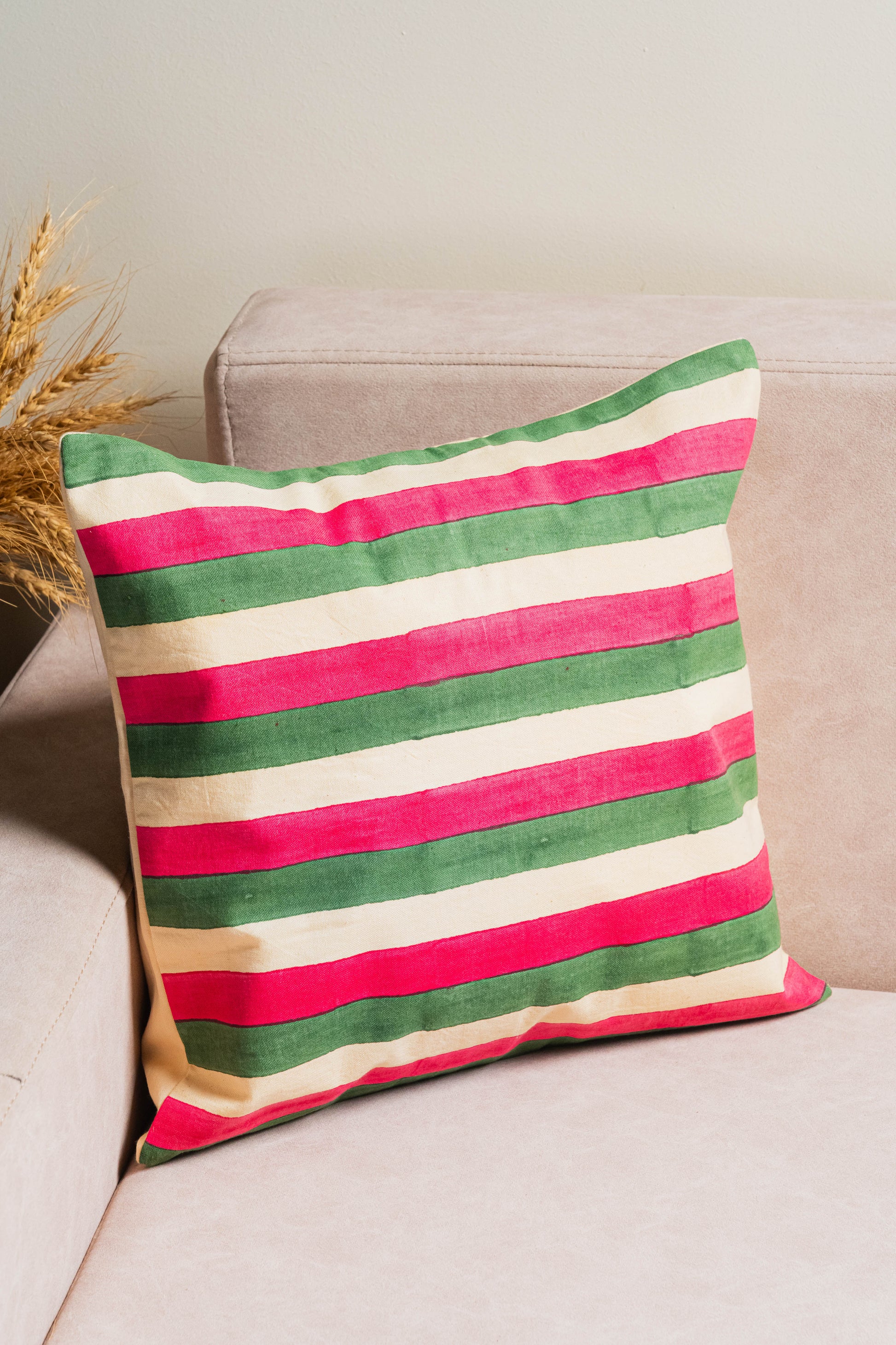 Striped pillow with red, green, and beige colors on a beige couch.