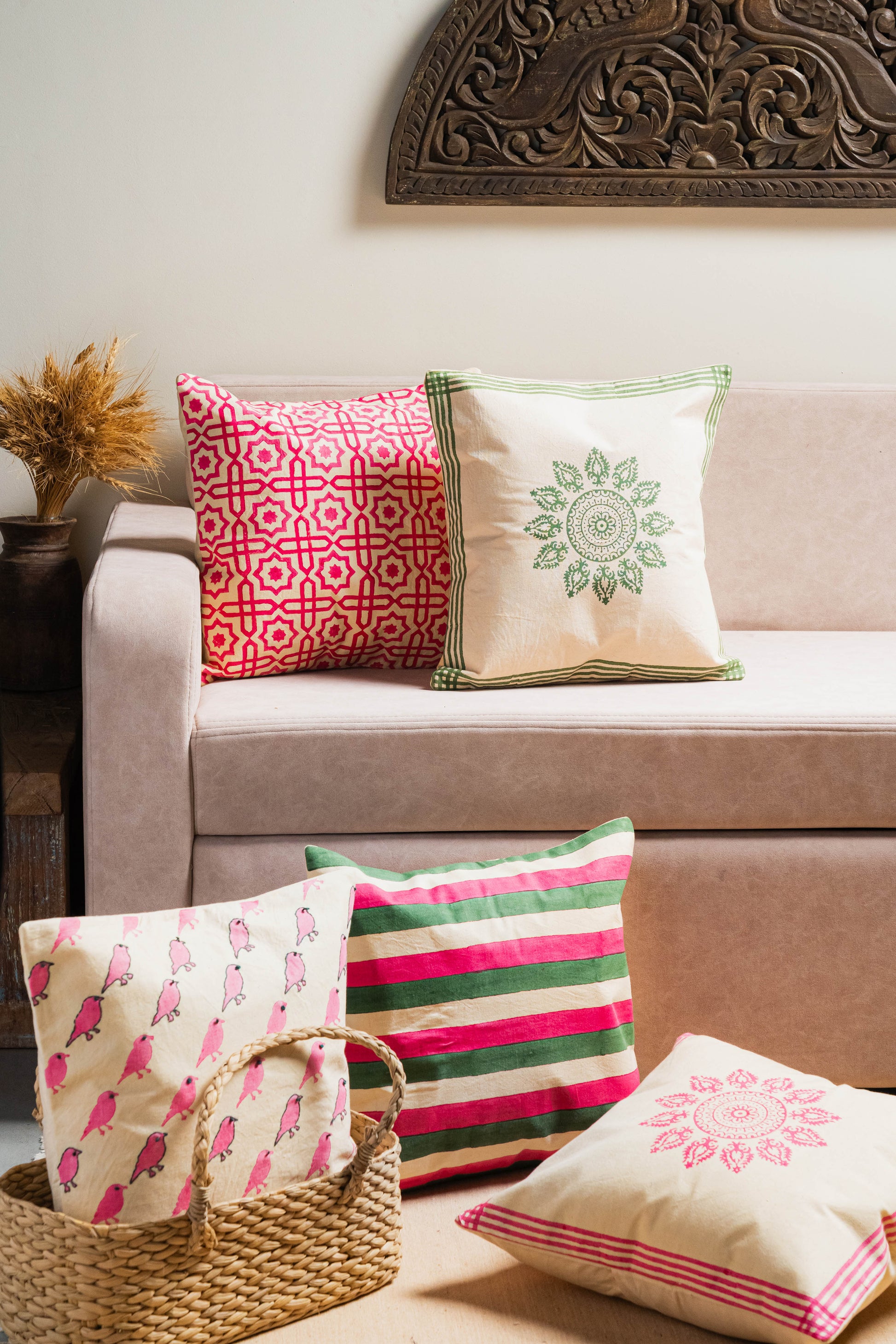 Decorative pillows on a beige sofa with a decorative wall piece.