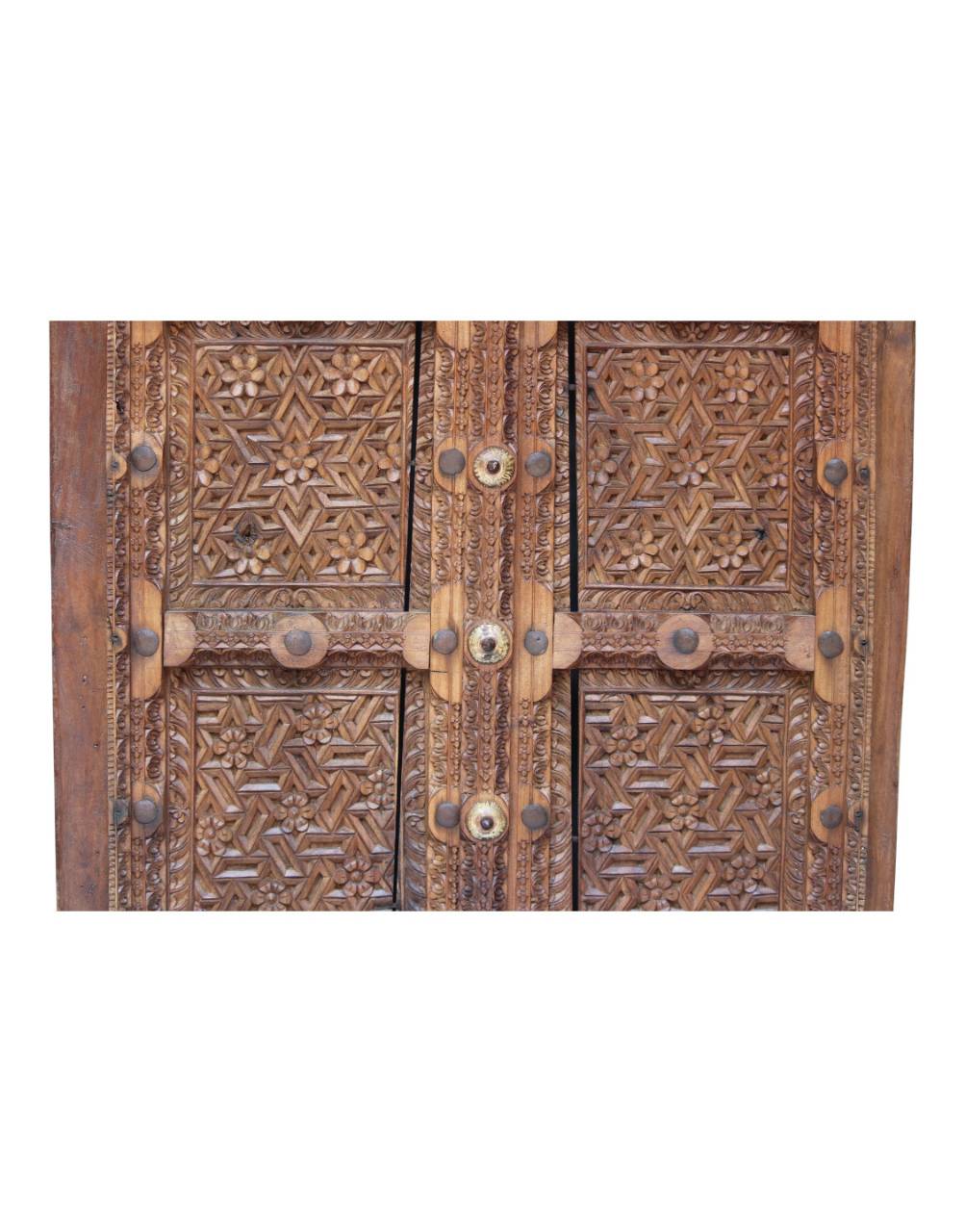 Close-up of ornate carved wooden doors with intricate geometric and floral patterns, metal hinges, and round metal studs on a white background.