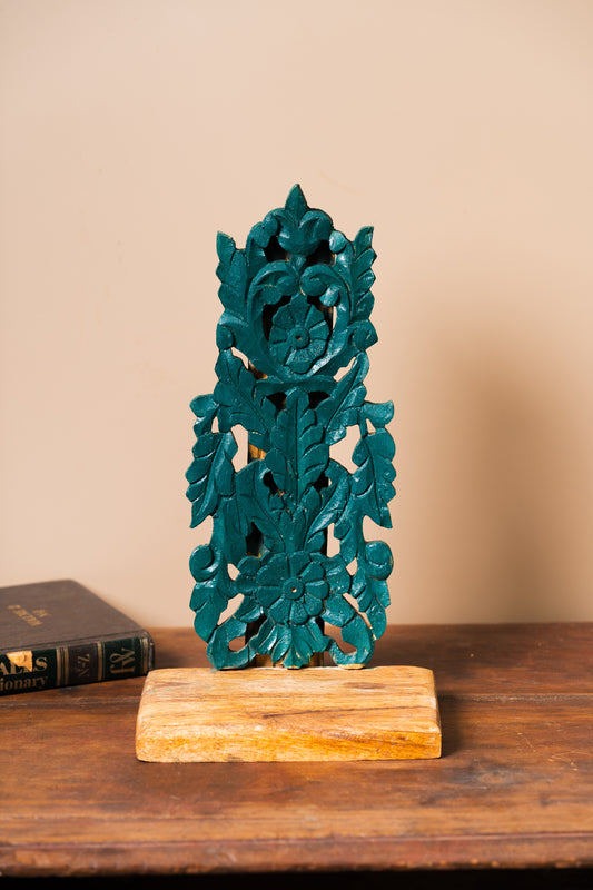 Hand-carved wooden stand, Green wooden stand, Functional art stand, Plant holder stand, Decorative object stand, Brass artefact display, Skilled artisan stand, Rustic wooden stand, Ornate wooden stand, Natural motif carving, Geometric pattern stand, Cultural symbol décor, Green finish stand, Wall-mounted stand, Tabletop display stand, tesu 