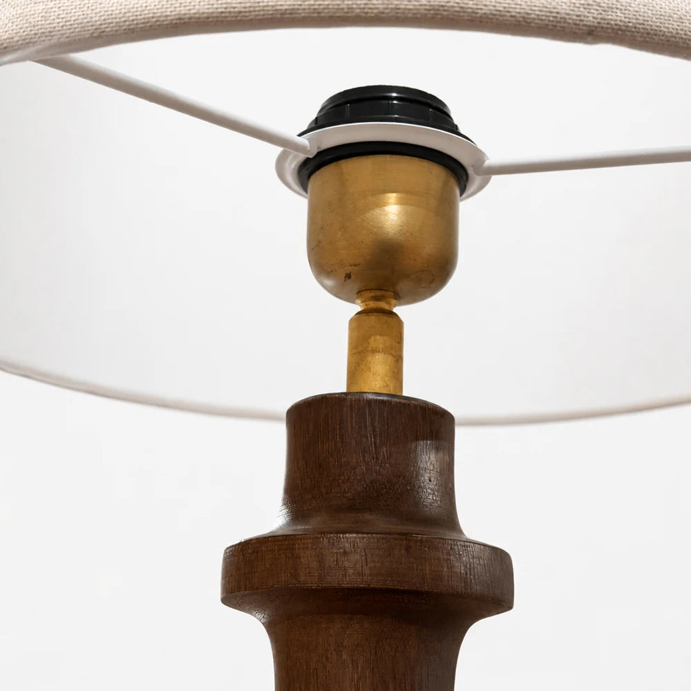 Close-up of a wooden lamp base with a white shade on a light gray background
