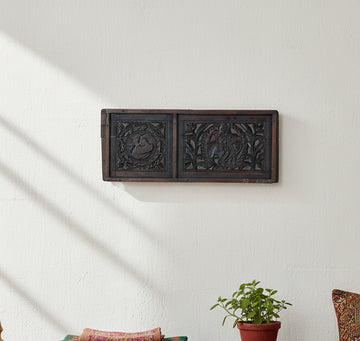 An antique carved wooden panel with two rectangular sections, featuring intricate relief carvings of a swan and a figure in foliage, finished in dark brown wood.