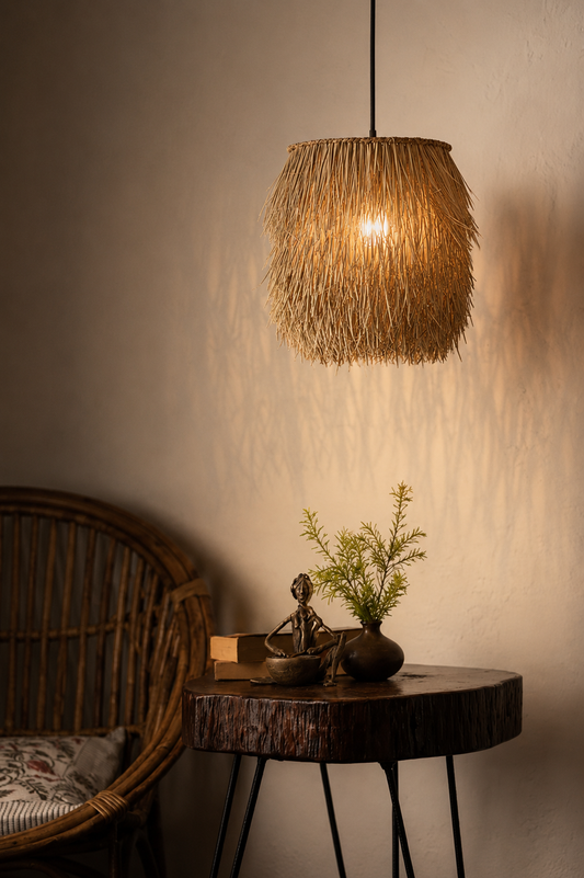 A bohemian-style woven rattan pendant light glowing warmly, hanging above a rustic wooden side table in a dimly lit room with a wicker chair partially visible.