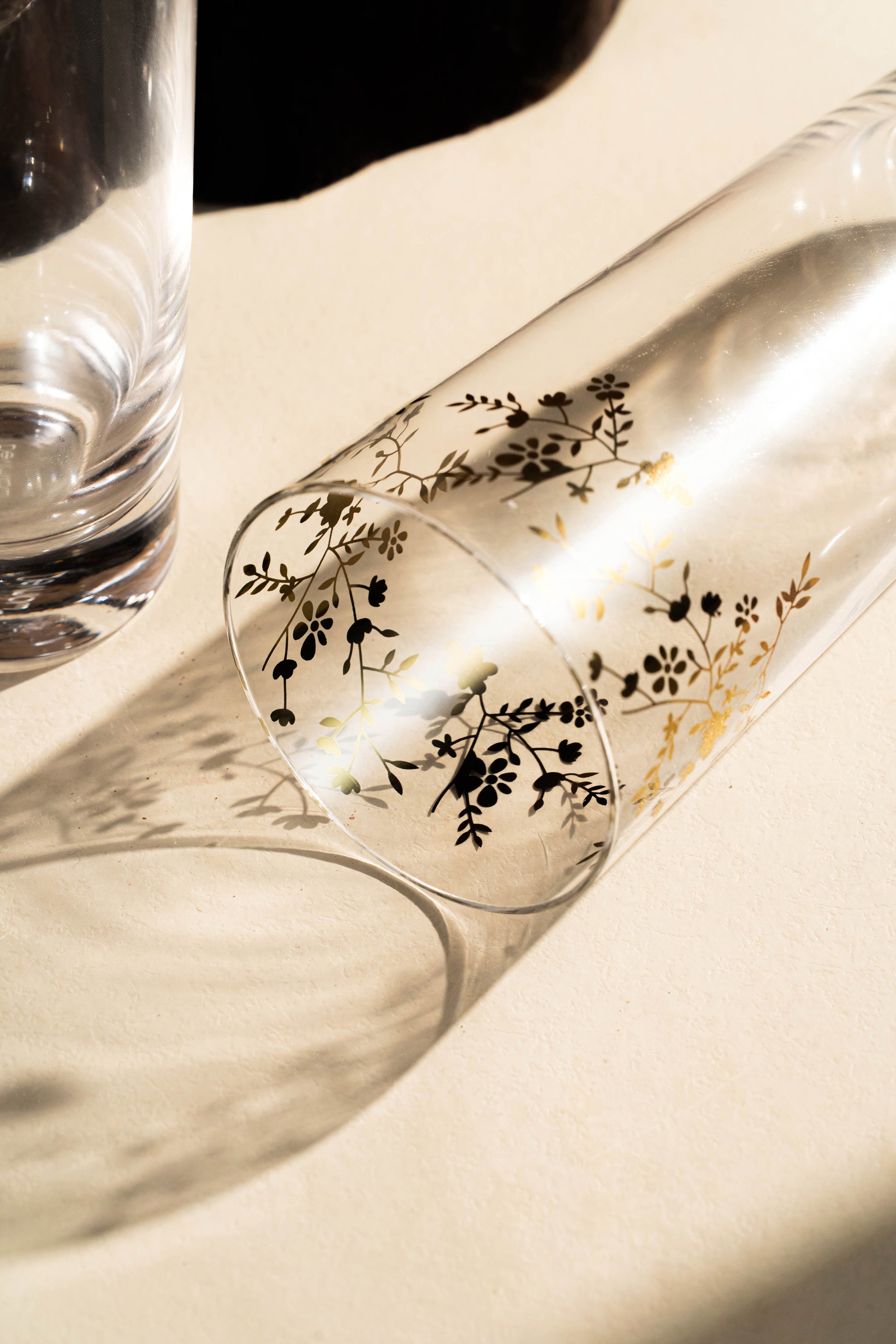 Clear glass with giolden floral design on a white surface