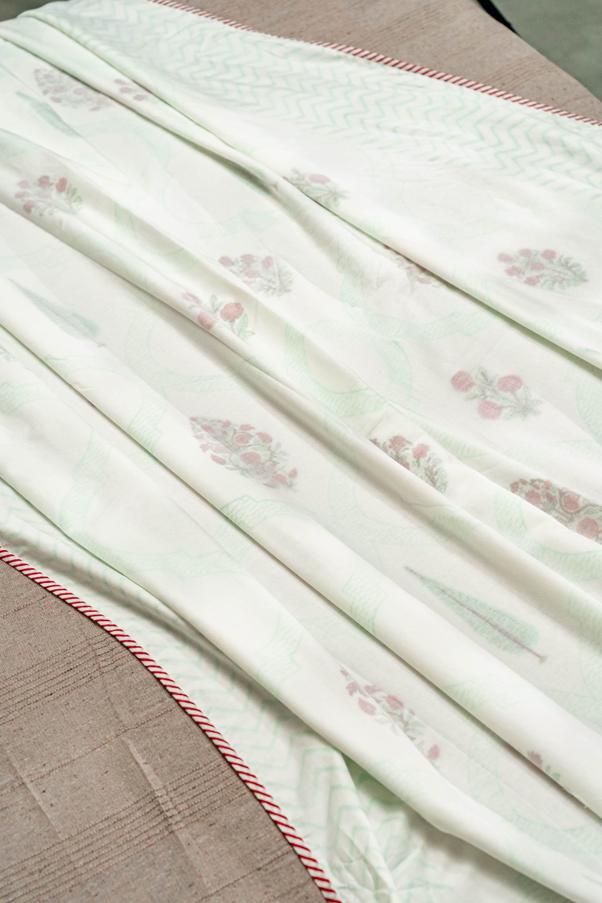 Three layers of fine muslin are stitched together in which the middle layer is hand block printed and edged with a striped flange.