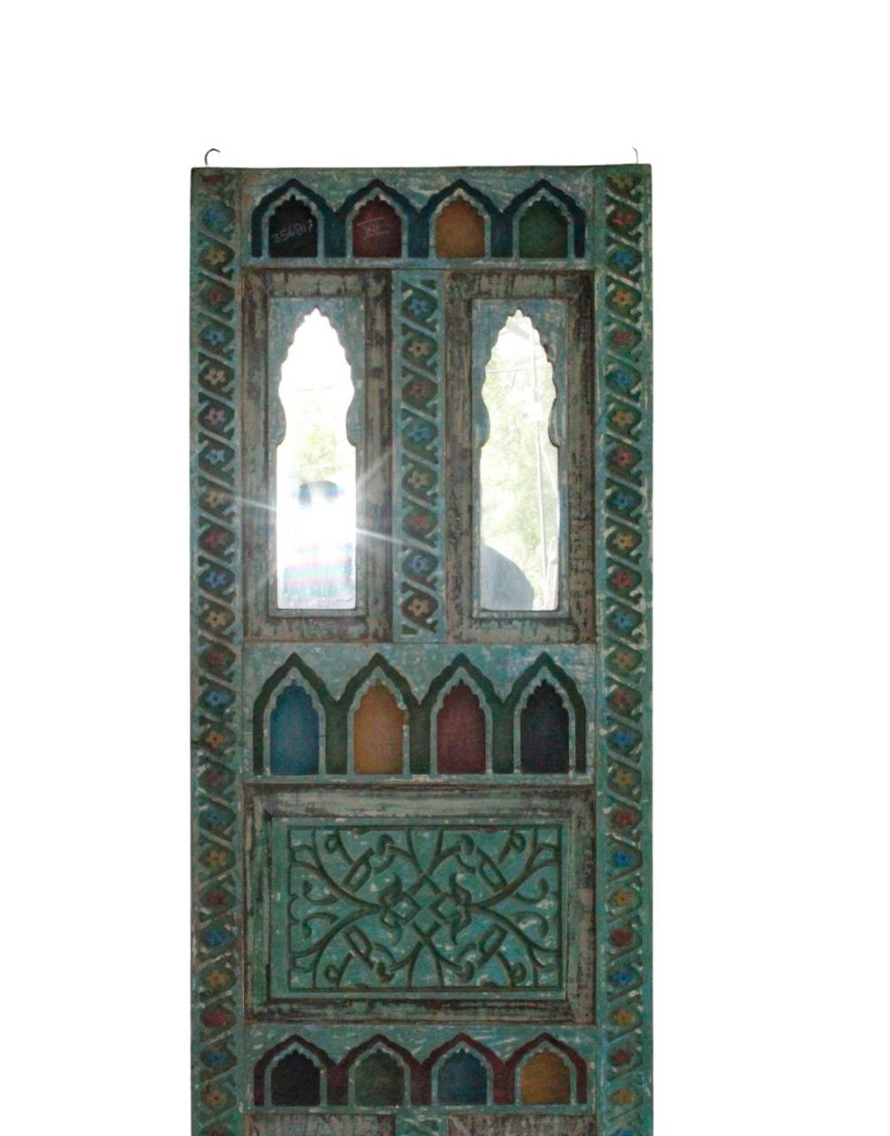 An ornate rectangular wooden door panel with intricate carved patterns and multiple arched window cutouts, featuring a distressed teal-green finish with small multicolored accents, shown against a plain white background.