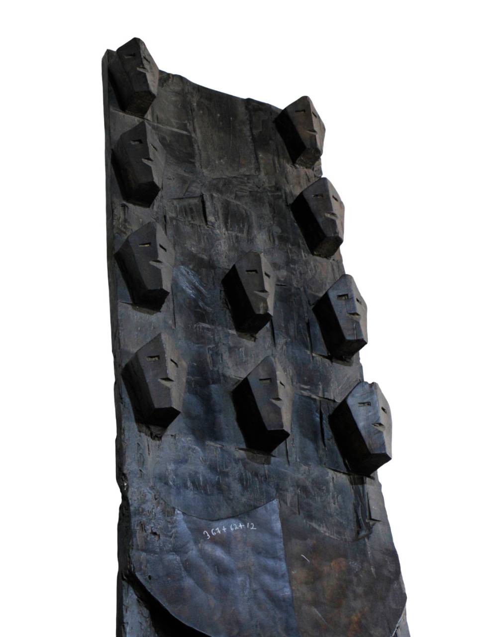 A dark, abstract sculptural wall art piece featuring a tall, textured rectangular form with repeated faceted geometric protrusions, shown against a plain white background.