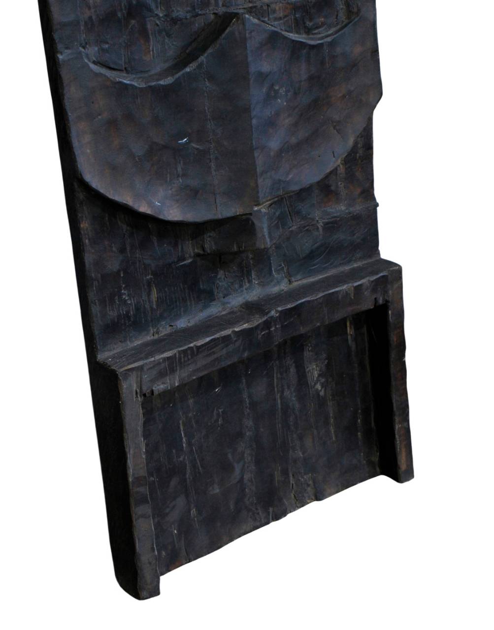 A close-up of a dark carved wooden object, showing textured wood grain and a recessed rectangular opening, isolated on a white background.