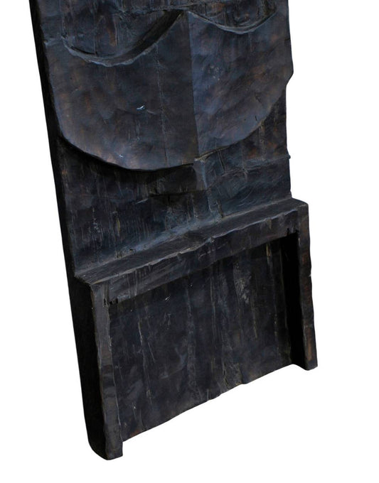 A close-up of a dark carved wooden object, showing textured wood grain and a recessed rectangular opening, isolated on a white background.