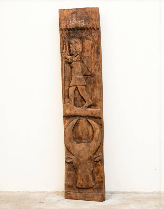 Wooden panel with carvings of a figure and a bull on a white background