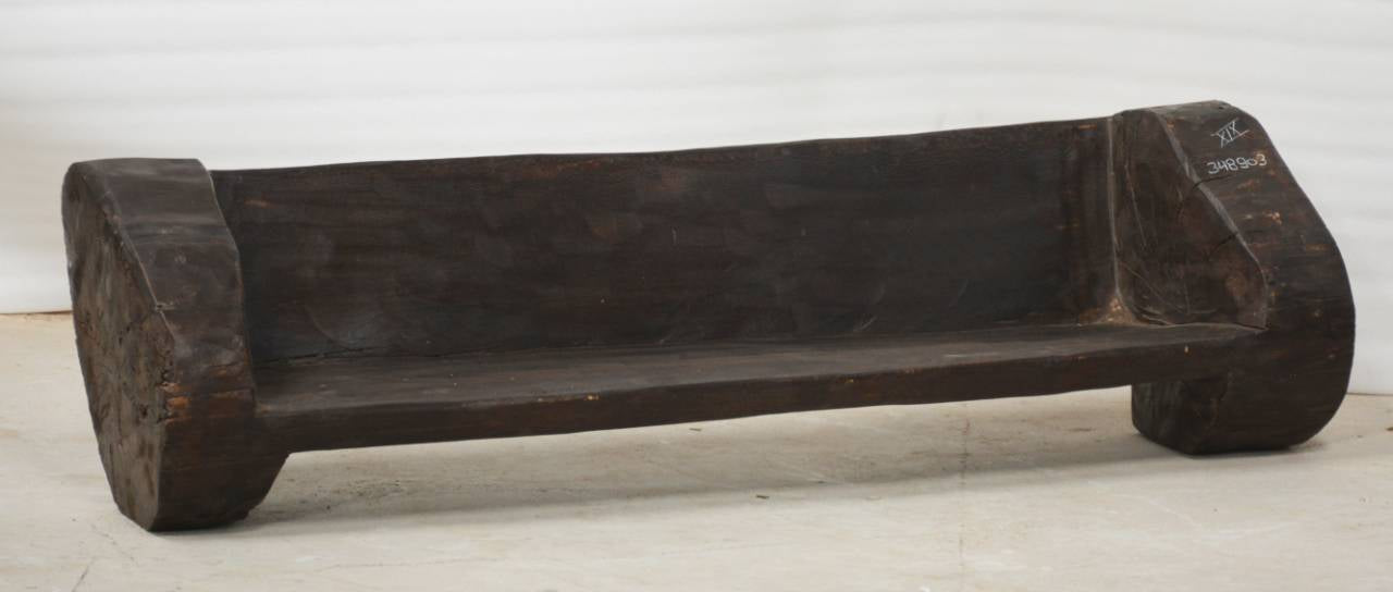 Wooden bench with a dark brown finish on a light wooden floor.