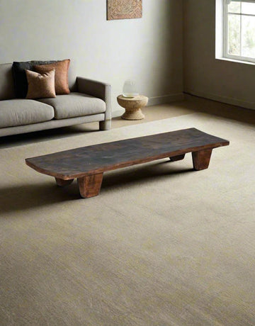 Wooden coffee table in a living room with a sofa and decorative items.