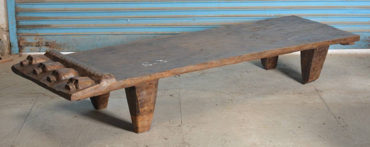 Wooden bench with rustic design on a concrete floor.