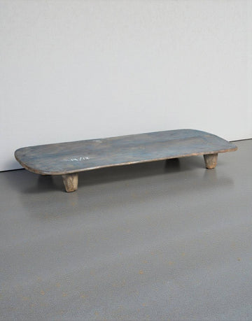 Wooden shelf with a blueish tint on a gray floor against a white wall