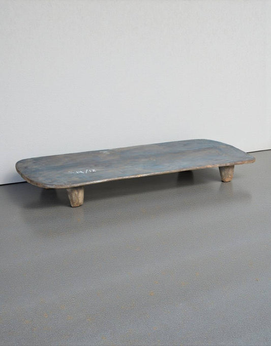 Wooden shelf with a blueish tint on a gray floor against a white wall