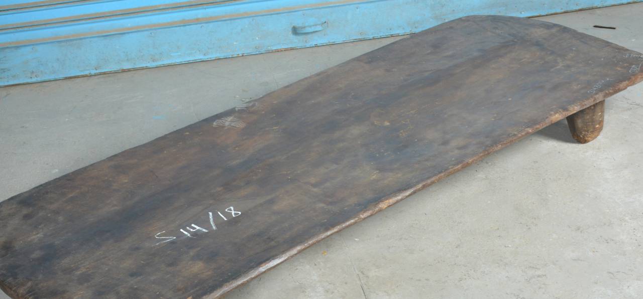 Wooden skateboard deck with visible wear on a concrete surface