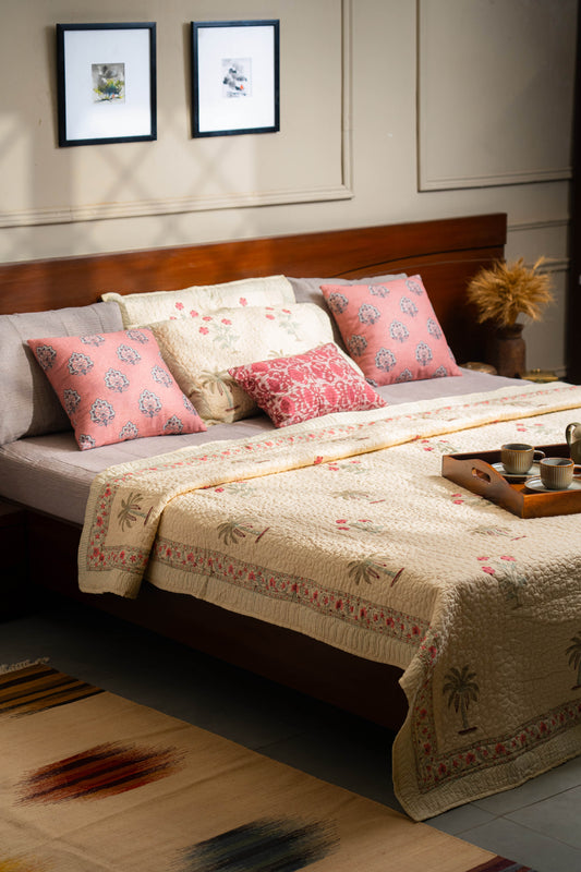 Bedroom with a bed featuring floral pillows and a decorative blanket, with a tray of cups on a nightstand.
