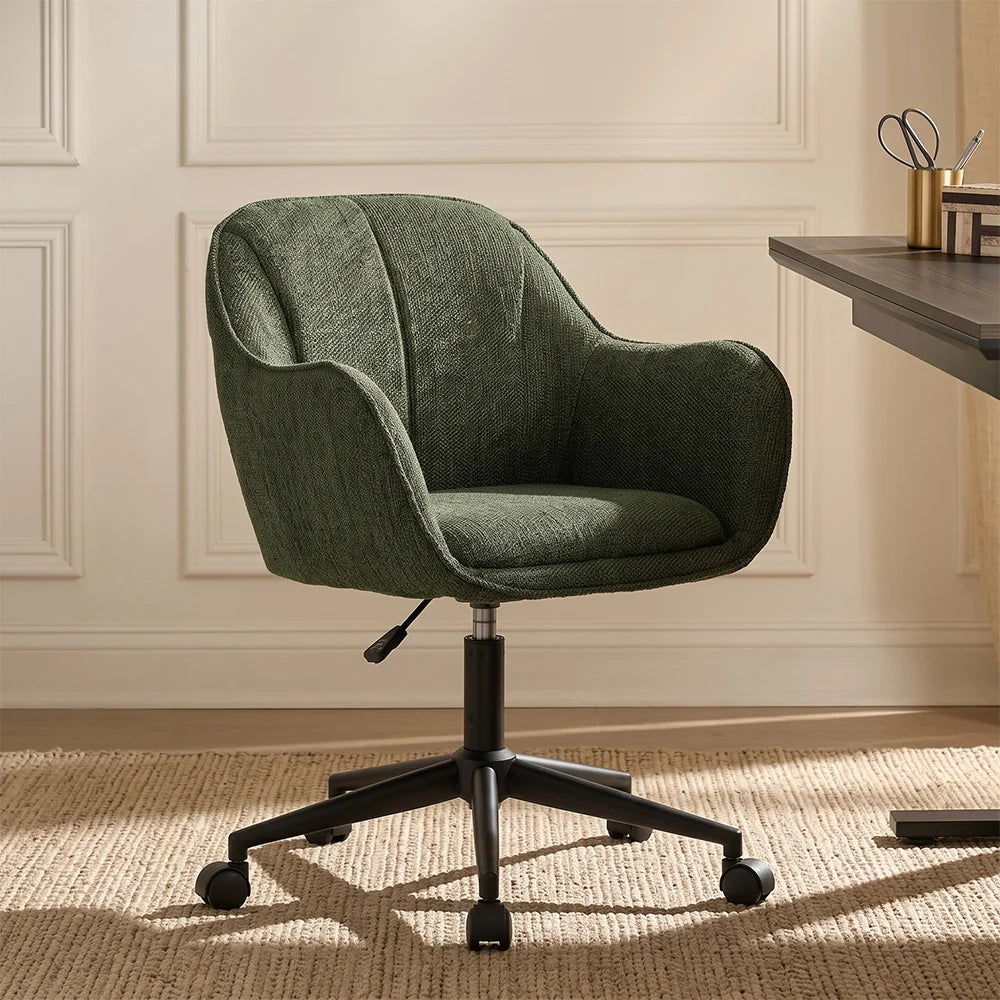 A green upholstered swivel office chair with a black five-star base and casters, placed in a home office setting next to a wooden desk.