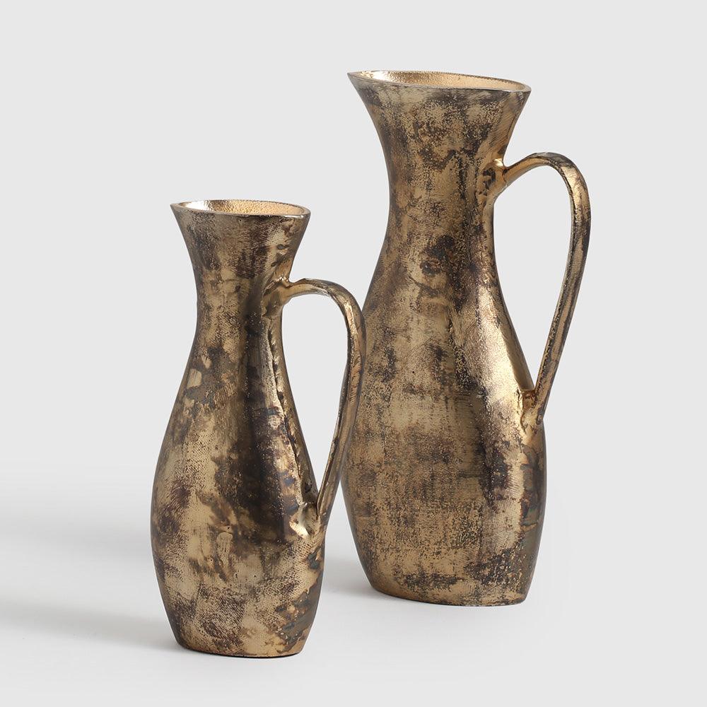  this pair of handcrafted aluminium vases showcases a graceful pitcher-inspired silhouette adorned in a rich, antique gold finish. 