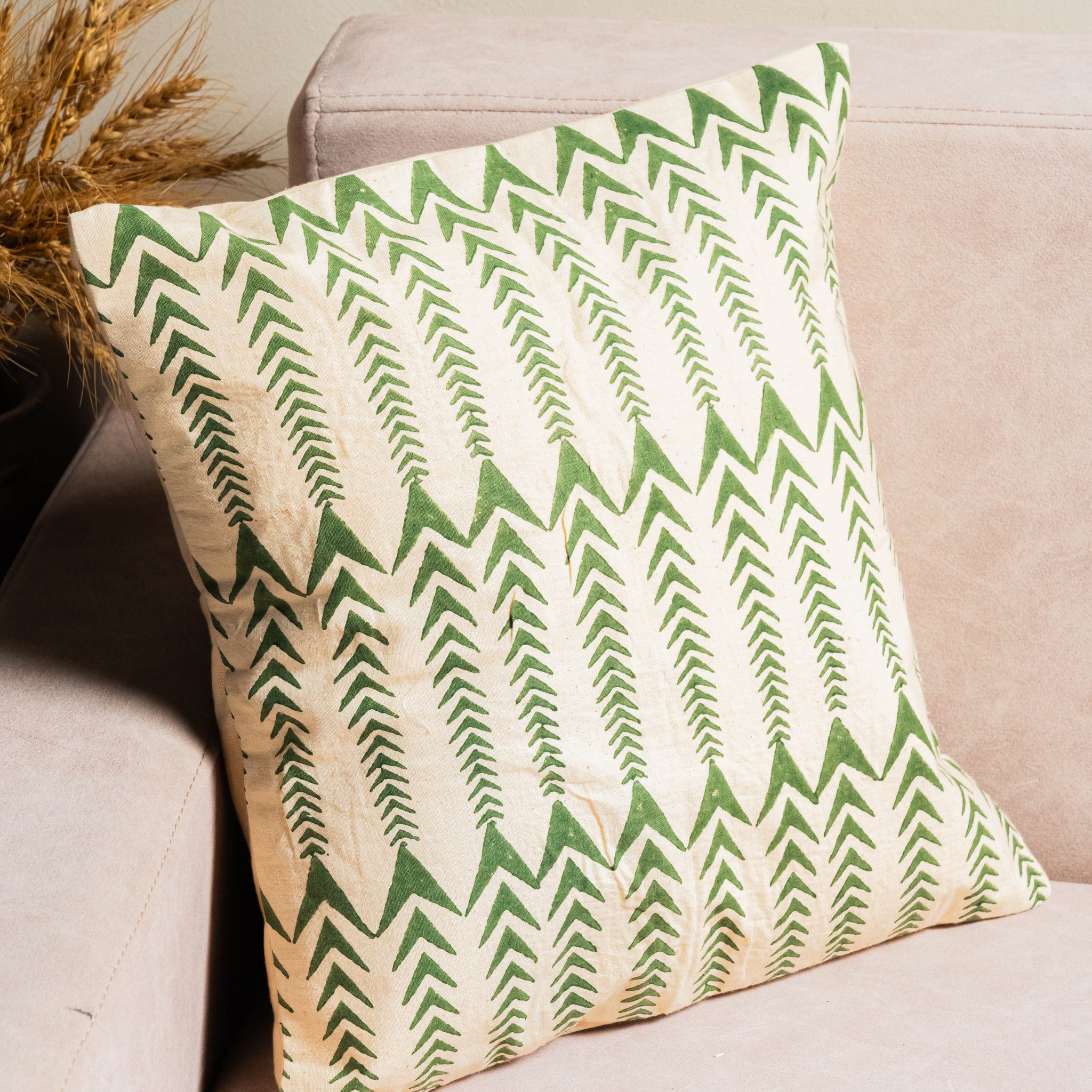 Green and beige patterned pillow on a beige sofa