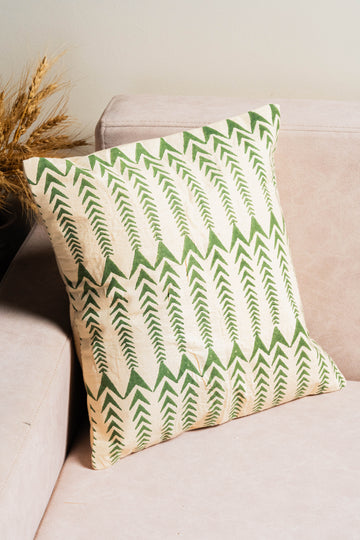 Green and beige patterned pillow on a beige sofa