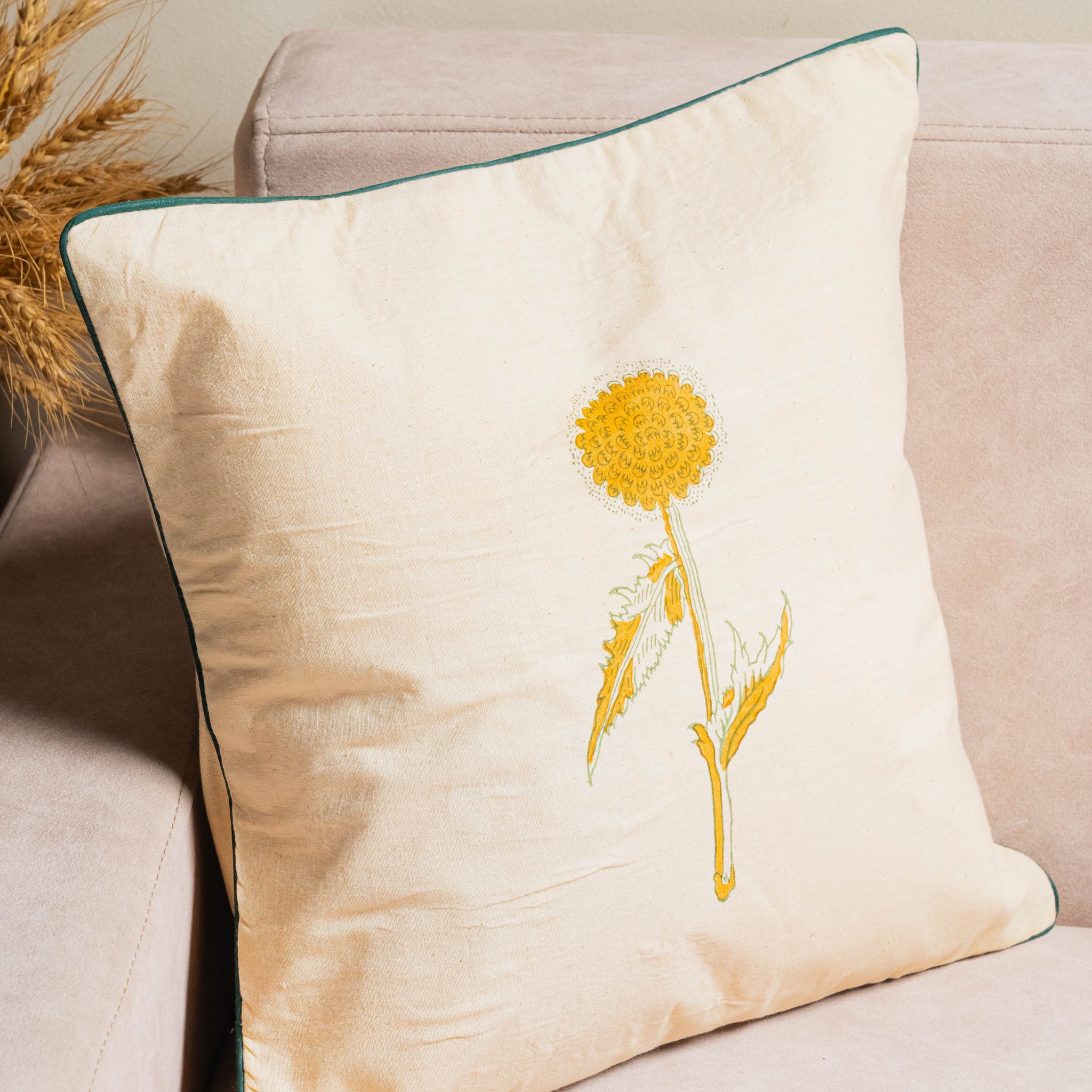 Decorative pillow with a yellow flower design on a beige couch.