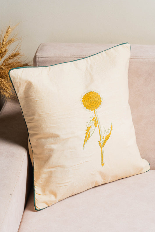 Decorative pillow with a yellow flower design on a beige couch.