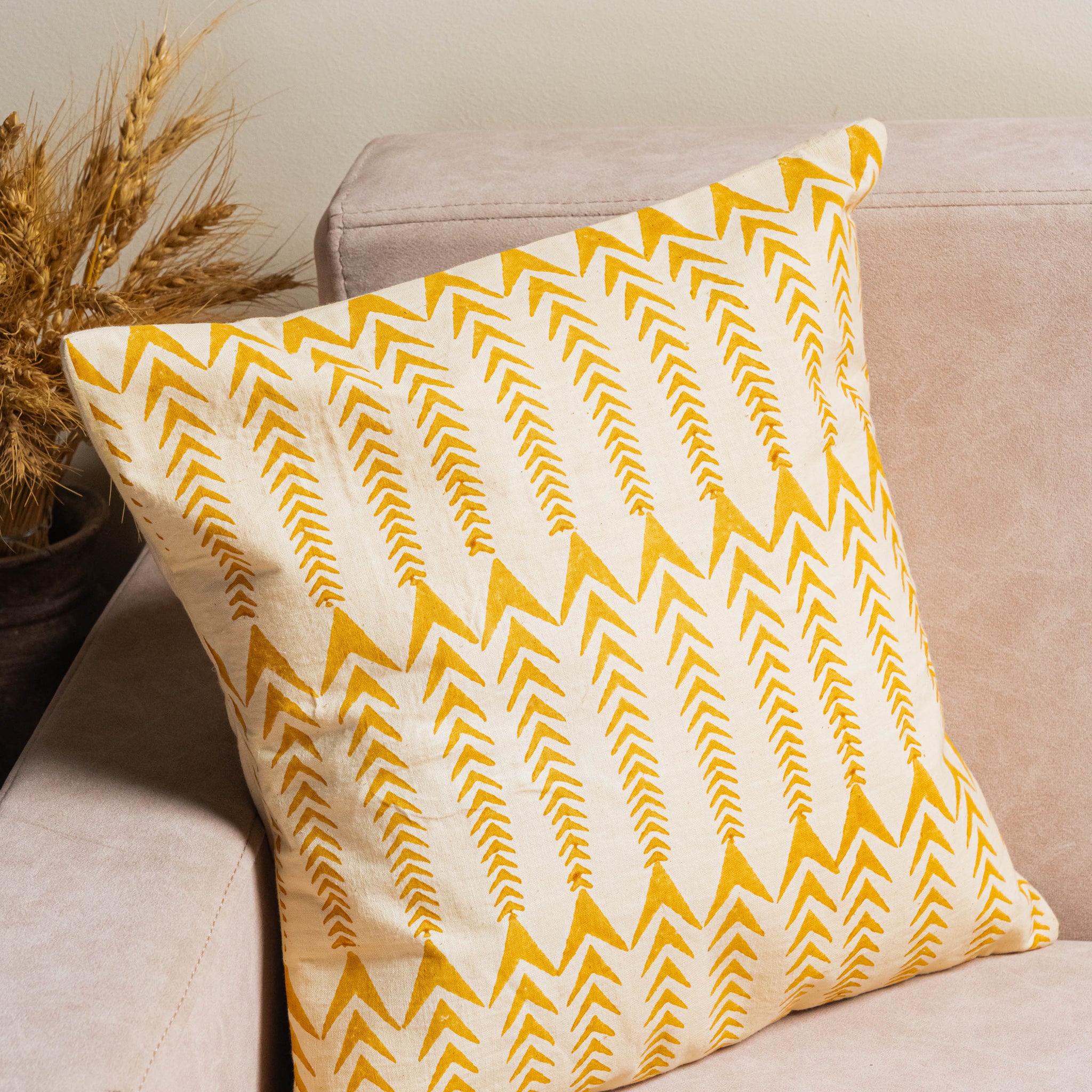 Yellow chevron patterned pillow on a beige couch with a neutral background