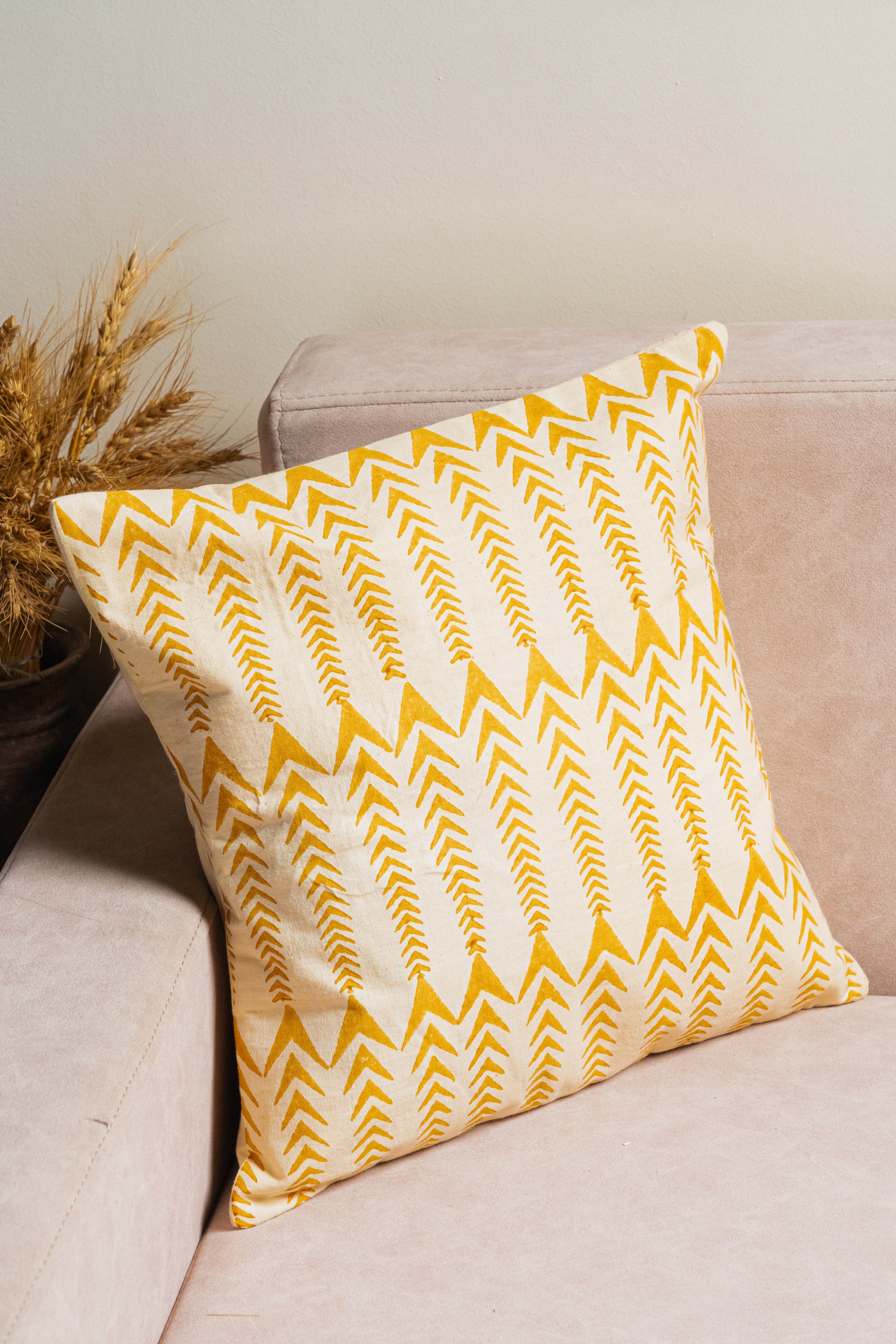 Yellow chevron patterned pillow on a beige couch with a neutral background
