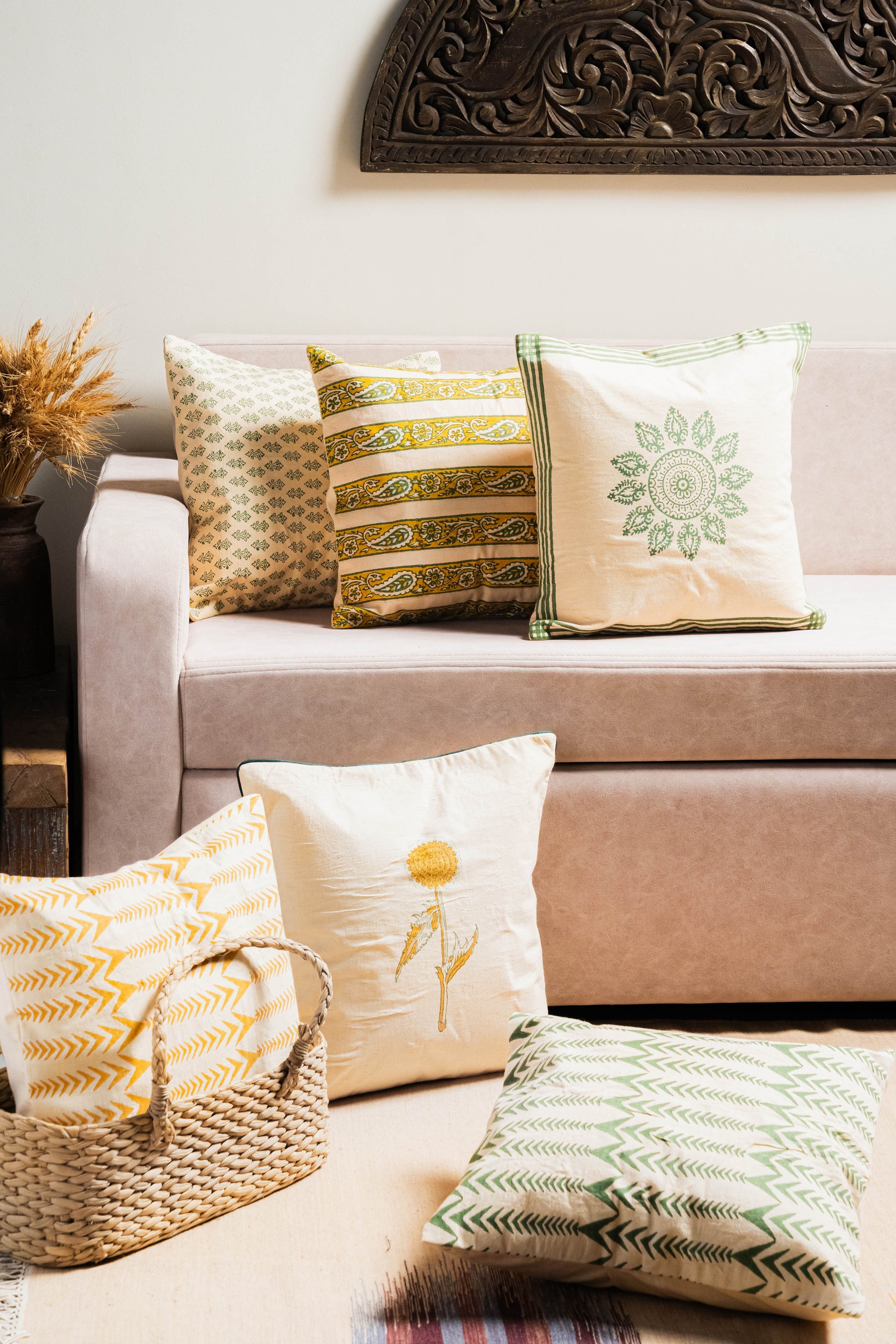Decorative pillows on a beige sofa with a decorative wall piece above.