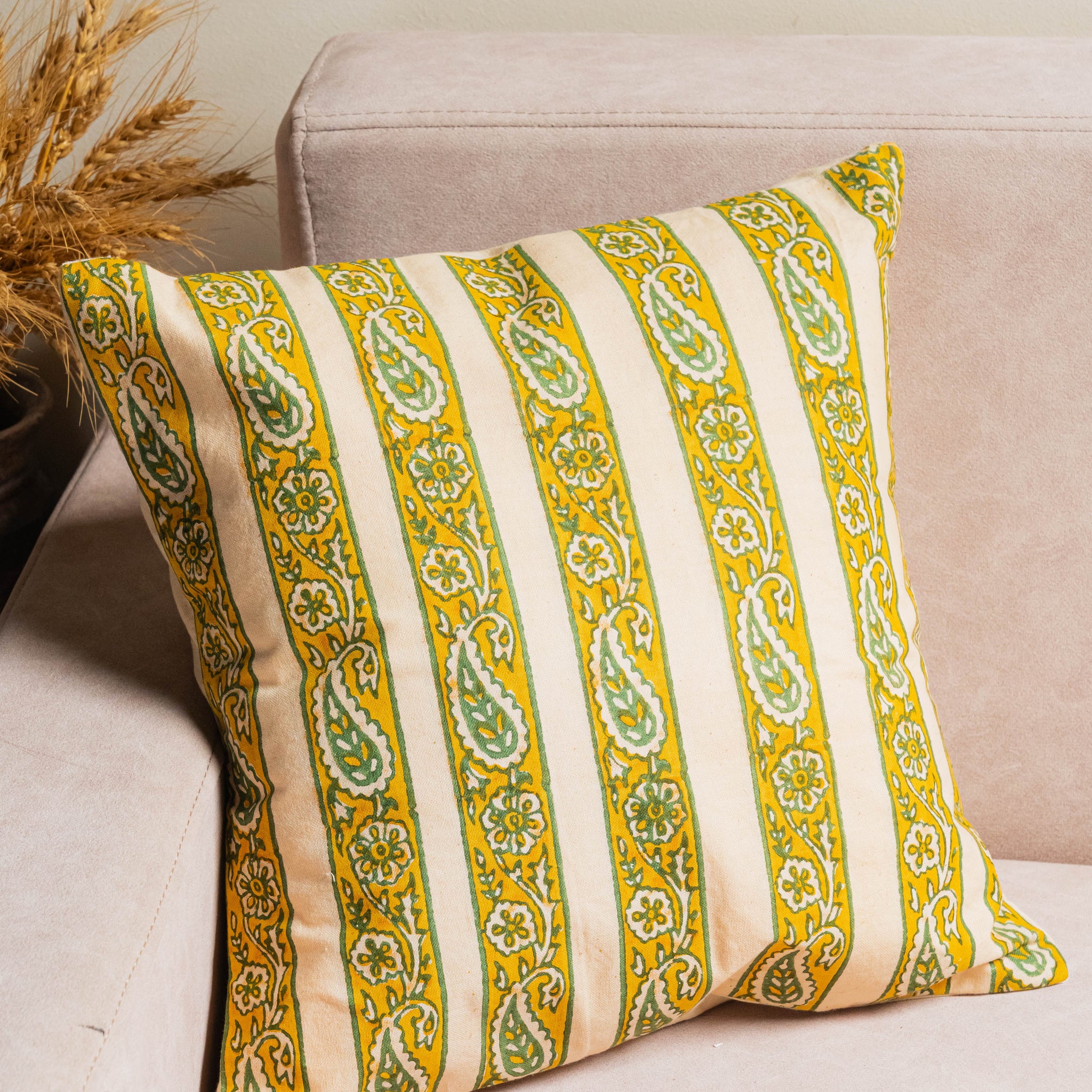 Decorative pillow with yellow and green stripes on a beige couch.