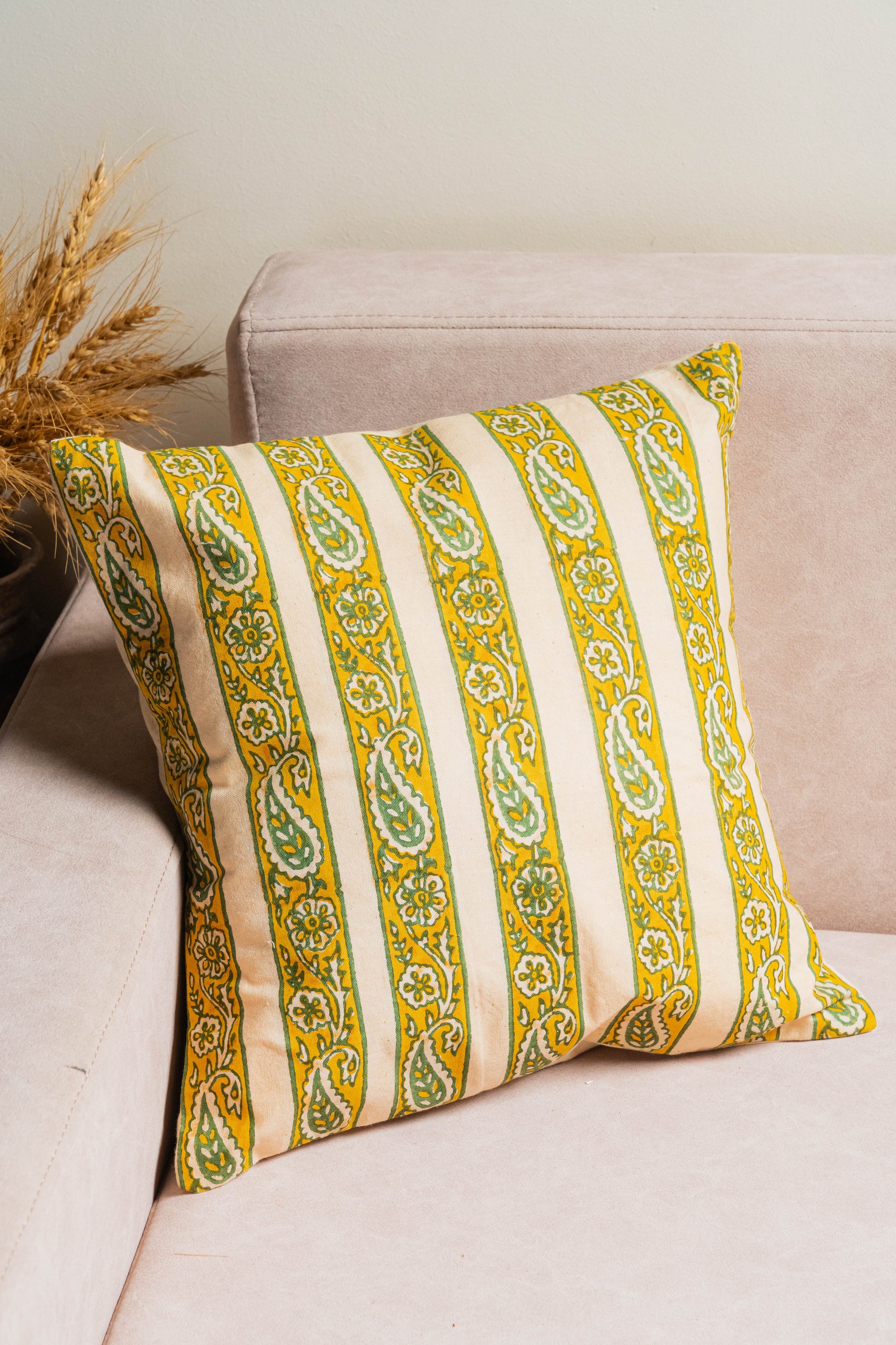 Decorative pillow with yellow and green stripes on a beige couch.
