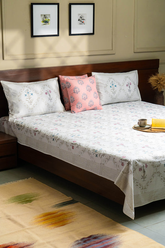 Bed with floral bedding and pillows in a room with framed pictures on the wall.