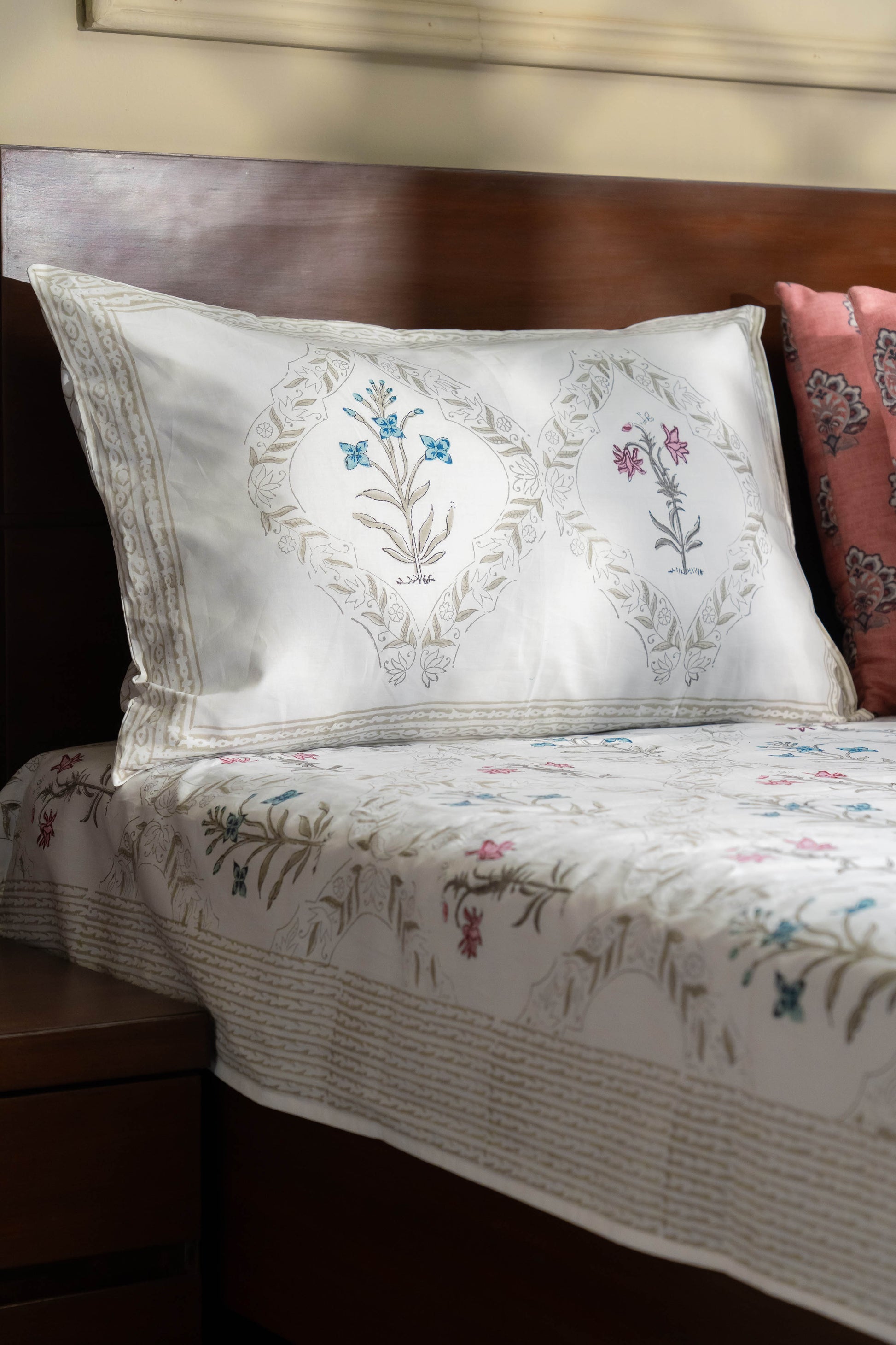Floral embroidered pillow and bedding on a bed with wooden headboard