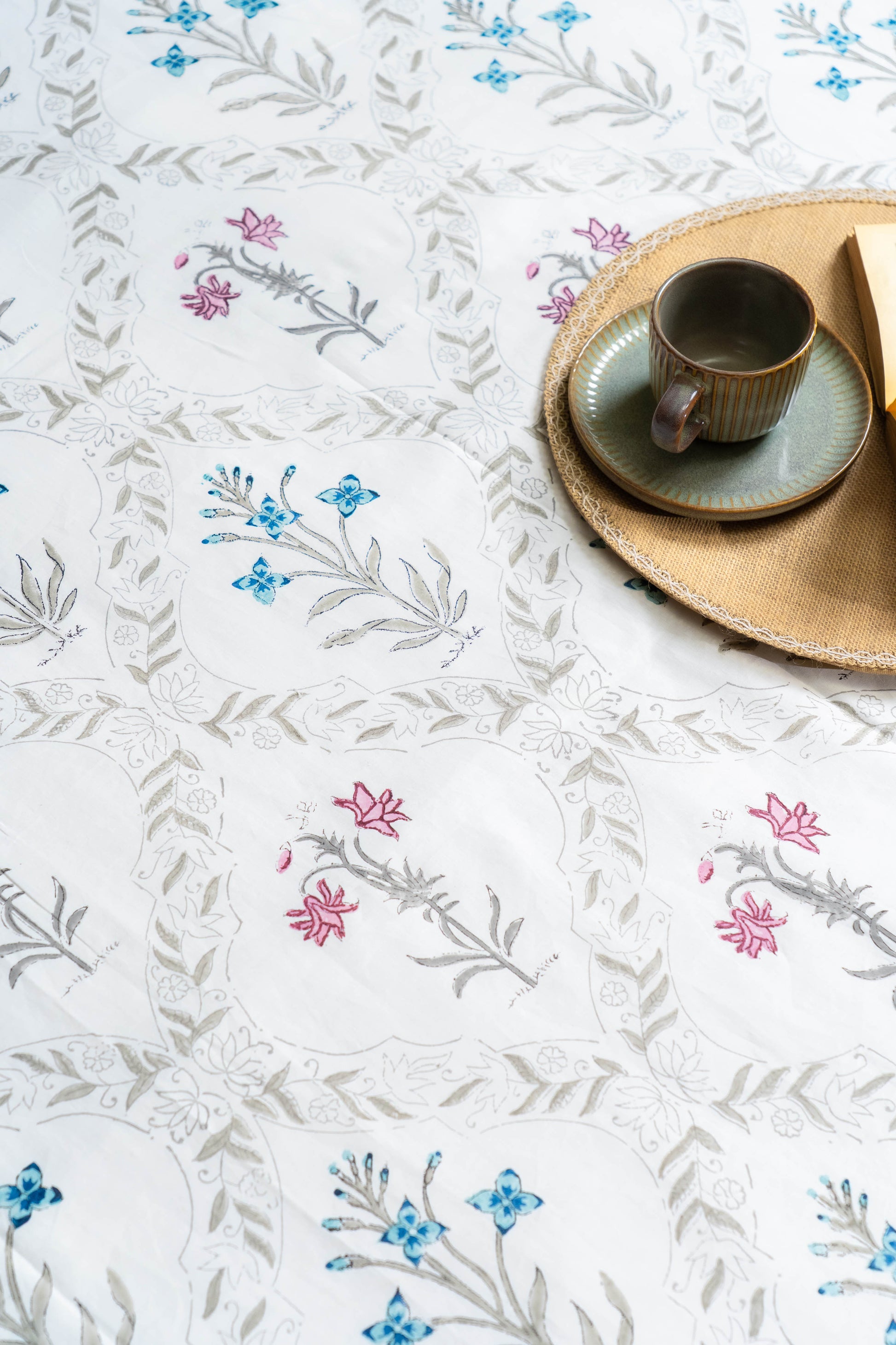 Tablecloth with floral patterns and a cup and saucer on a table.