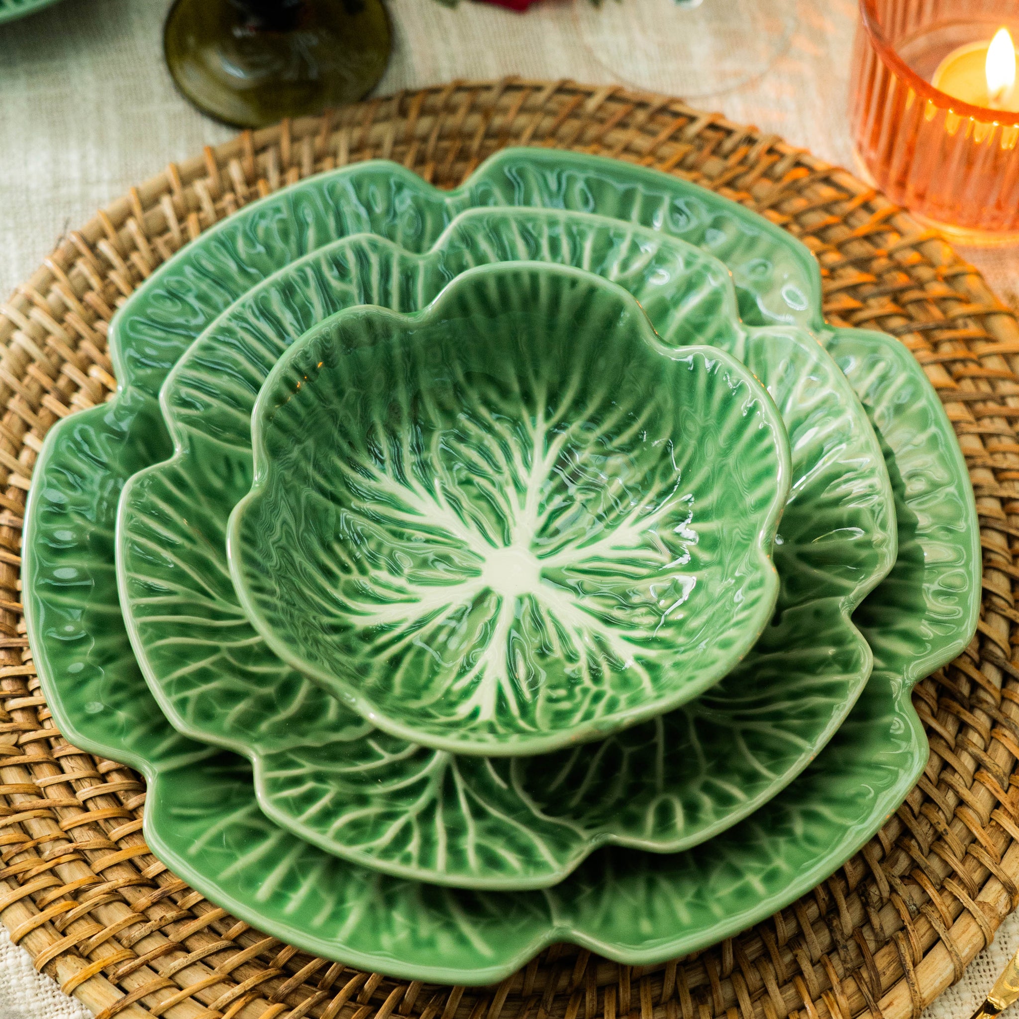 Set of green ceramic plates with floral patterns on a woven placemat.