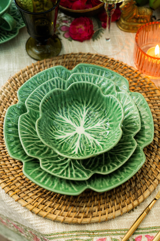 Set of green ceramic plates with floral patterns on a woven placemat.