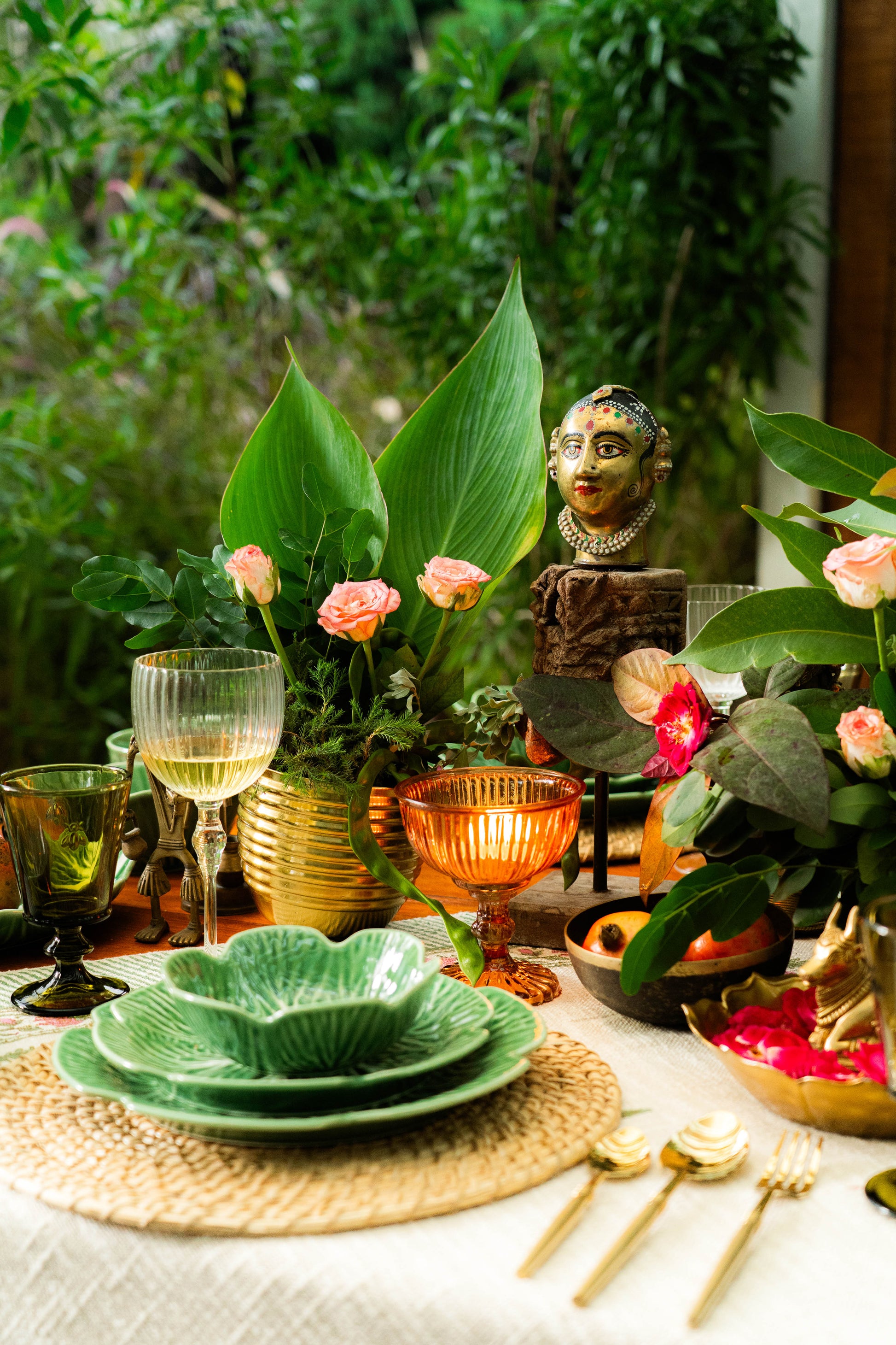 Decorative table setting with green plates, gold cutlery, and floral arrangements.