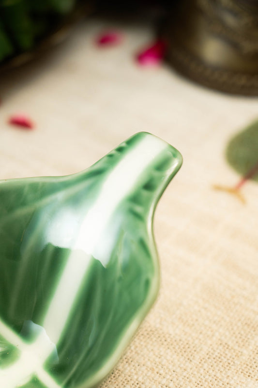 Close-up of a green ceramic object on a textured beige surface