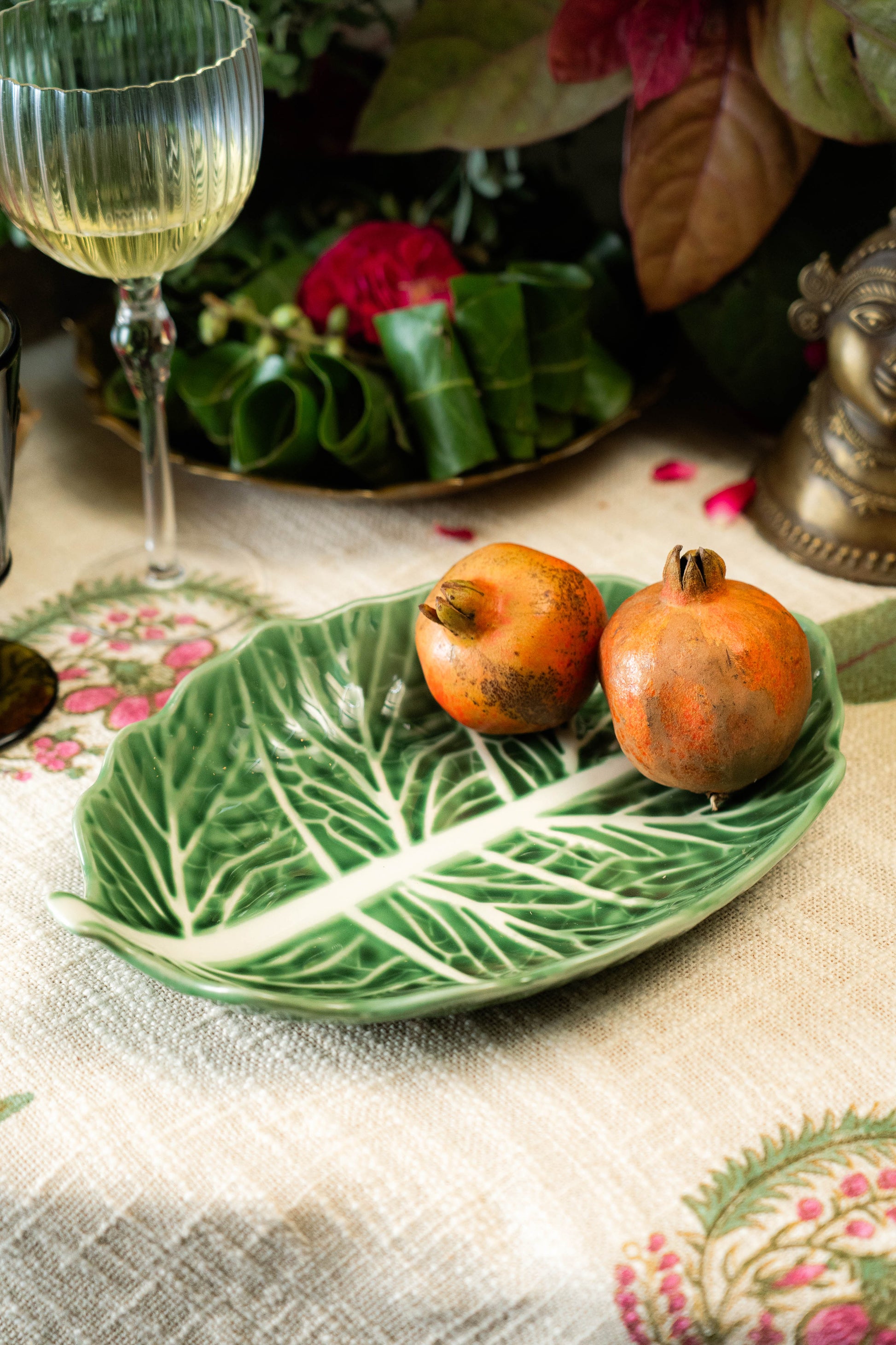 Decorative leaf-shaped plate with pomegranates on a tablecloth with floral patterns