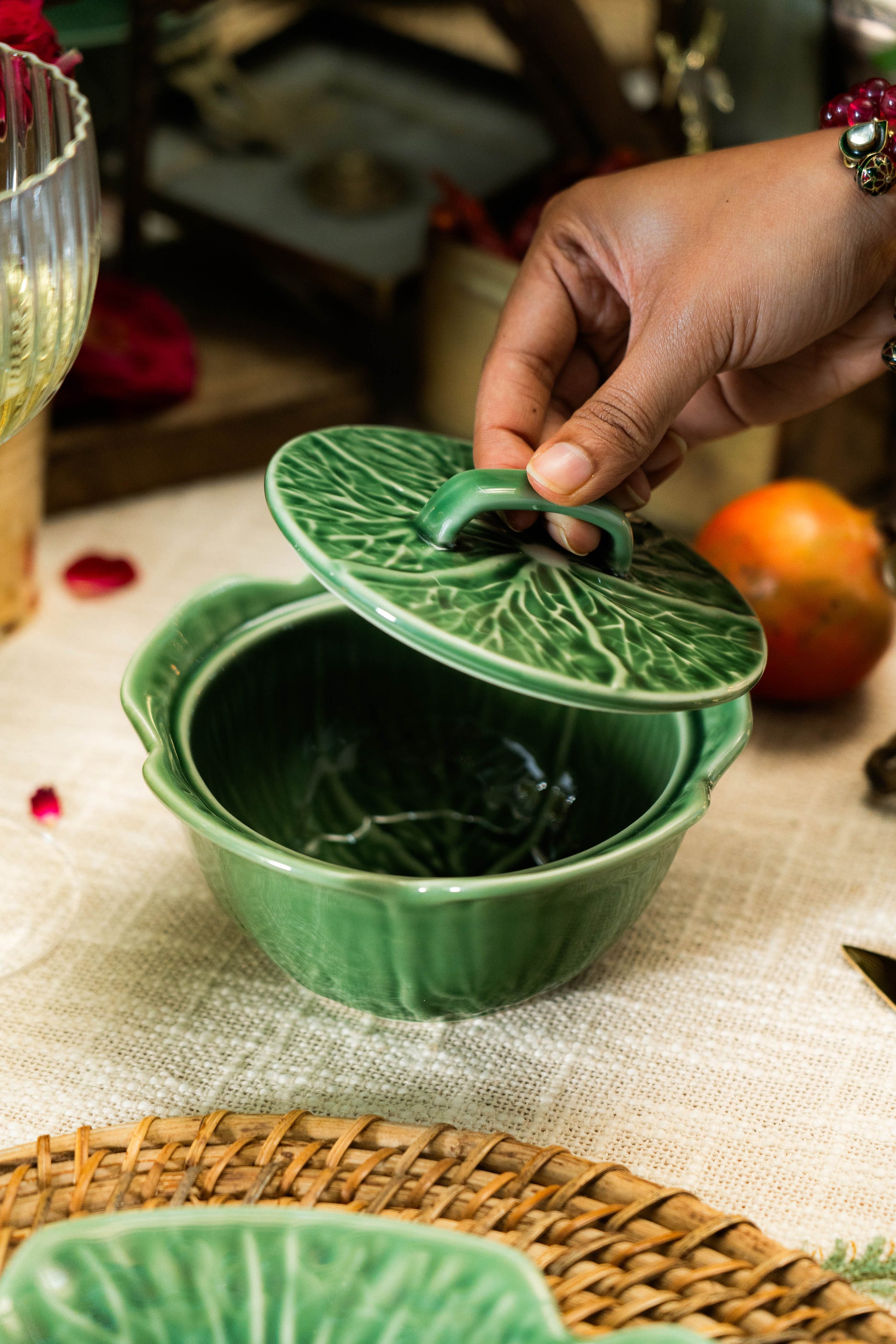 Green ceramic dish with leaf-shaped lid on a textured surface