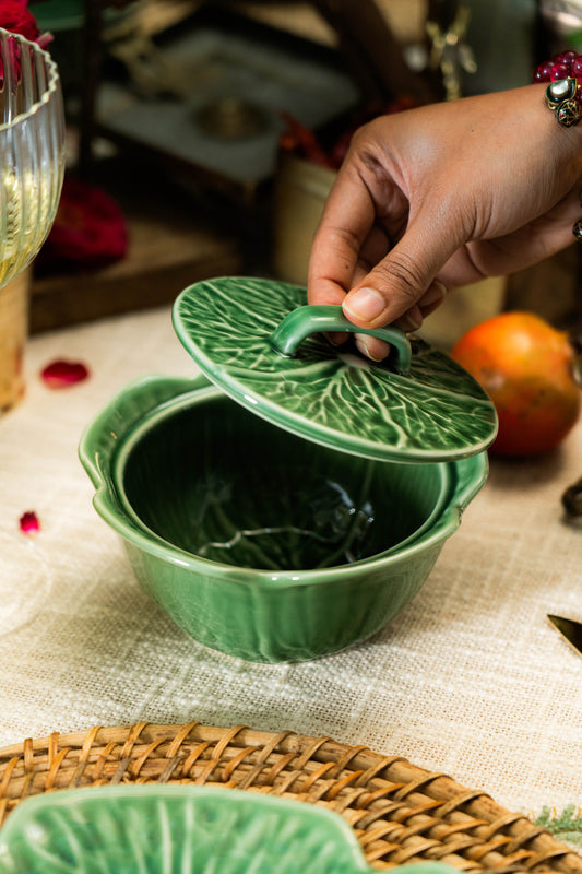 Green ceramic dish with leaf-shaped lid on a textured surface