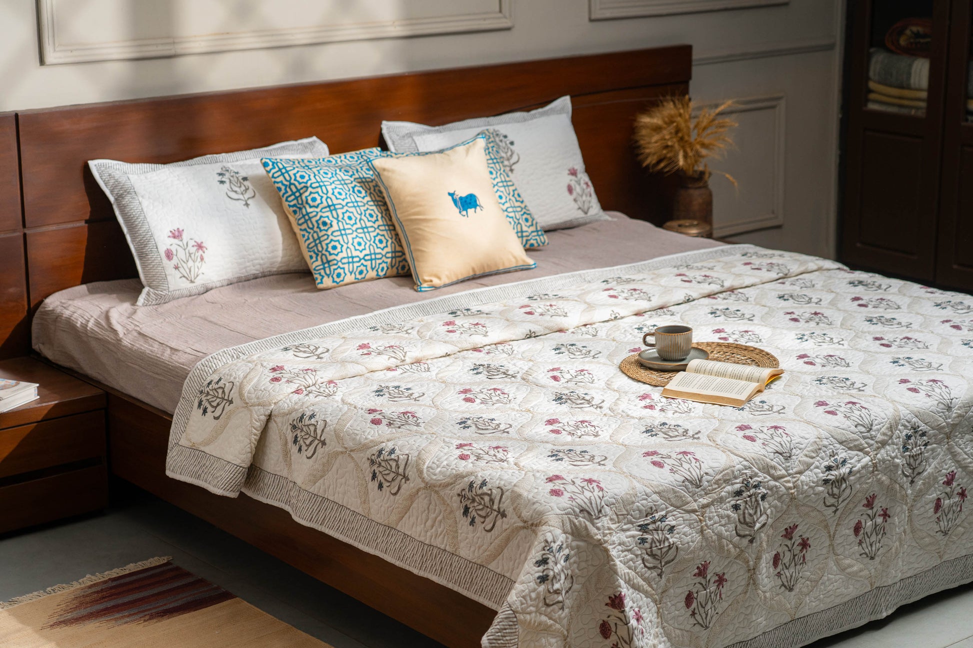 Bed with floral quilt and decorative pillows in a bedroom setting