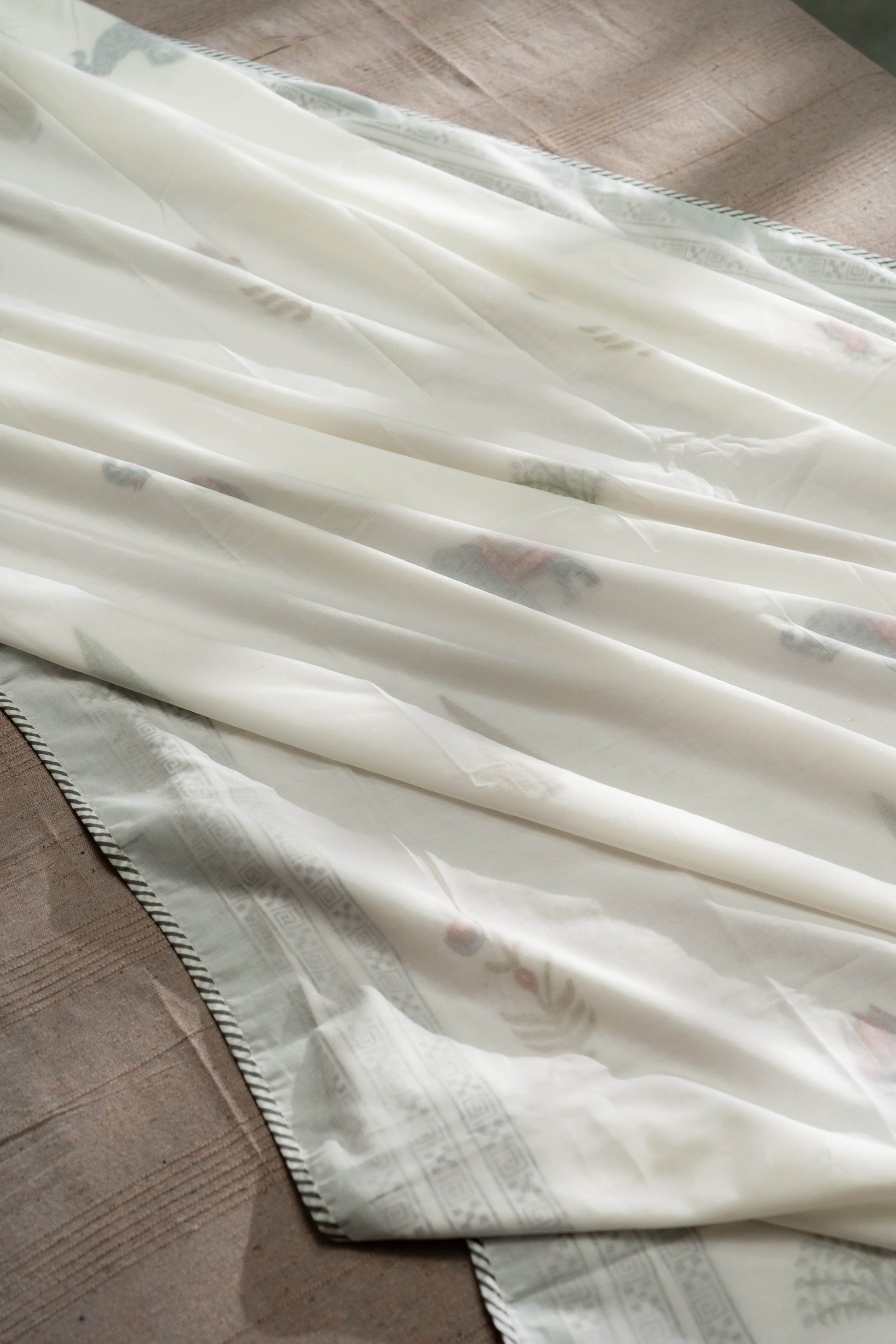 Three layers of fine muslin are stitched together in which the middle layer is hand block printed and edged with a striped flange.